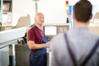 © pressmaster - Senior engineer consulting his young subordinate while standing by industrial machine in workshop