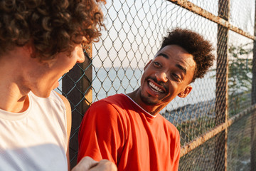 Two young cheerful multiethnic men basketball players