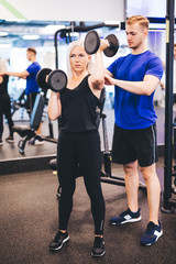 Wall Mural - Exercising woman assisted by personal trainer.