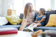 © pressmaster - Young mother and her little daughter sitting on sofa at home, relaxing and chatting