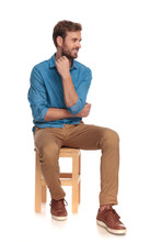 Pensive Young Casual Man Looks To Side While Sitting