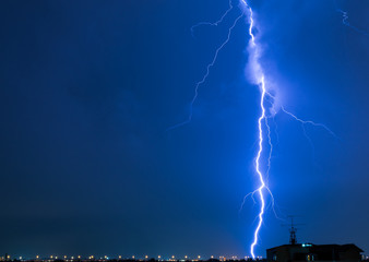 Severely lightning thundering down the center town. At the night with copy space.