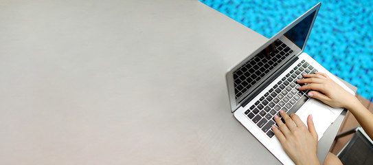Wall Mural - website banner of laptop with female hands, copy space in grey color and blue background. concept of