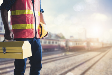 Construction worker or technician  holding tools box and helmet at soft blur train station background, ready to repair and fix concept