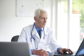 Senior male doctor working at consulting room