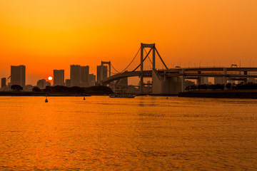 Fototapete - Tokyo skyline and rainbow bridge at sunset in Odaiba waterfront.