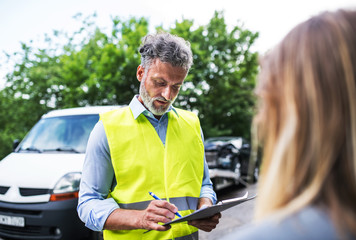 Wall Mural - An insurance agent talking to a woman outside on the road after a car accident.