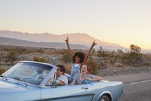 Group Of Friends On Road Trip Driving Classic Convertible Car 