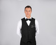 © New Africa - Portrait of young waiter in uniform on grey background