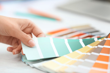 Woman with paint color palette samples at table, closeup