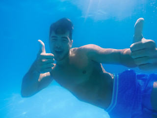 Wall Mural - Handsome young man swimming in pool, underwater view