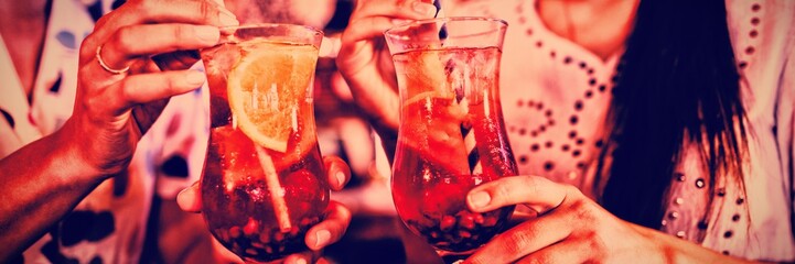 Mid-section of two young women having cocktail drinks