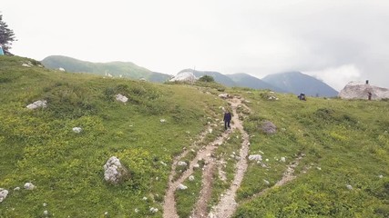 Wall Mural - woman walking on mountain trail while hiking tour drone view