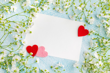 Blank card and three small hearts among gypsophial flowers