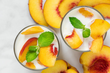 Wall Mural - peach yogurt with mint in glasses with fresh fruits on white marble table. healthy breakfast