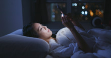 Woman Look At Smart Phone And Lying On Bed At Night