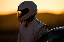 A Helmeted Driver Preparing To Race At Sunrise