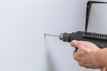 home renovation closeup hand using drill to drilling bit hole on the wall to install floating shelves