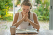© PhotoGranary - Christian worship and praise. A young woman is reading the Bible and praying in the early morning