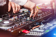 © luckyphoto - closeup hands of DJ at the control panel wearing in white shirt. disc jockey playing on the professional equipment at night club. concept of clubbing lifestyle