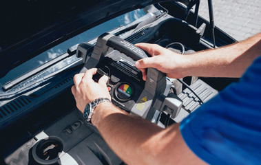 Accumulator charging. Hands and terminal. Car repair.