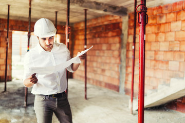 Wall Mural - Construction industry engineer working on house building site - reading paper plans and coordinating workers