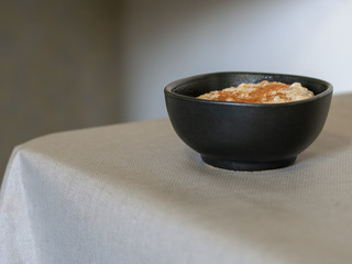 Just cooked authentic organic porridge in brown bowl on kitchen table. With cinnamon. Whole grain oats. Note narrow depth of field.