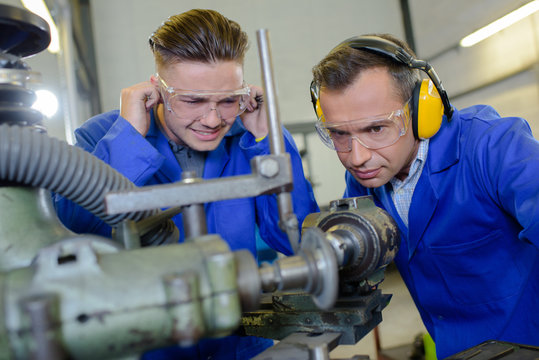 Apprentice protecting ears from noisy machine