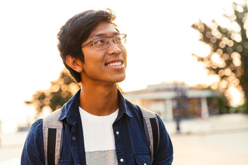 Wall Mural - Picture of Cheerful asian male student in eyeglasses looking away