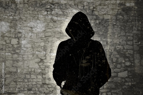 Cuadros en Lienzo Male black and white figure with hood on stone wall background