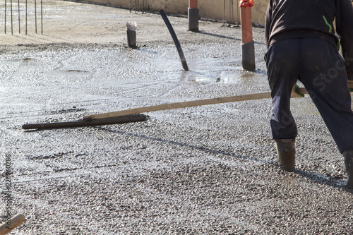 Worker In Rubber Boots Stands Uncluttered Cement And Leveling The Worker In Rubber Boots Stands Uncluttered Cement And Leveling The Surface Of Base Plate