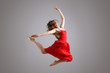 elegant female dancer in red dress jumping in the air