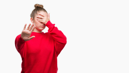 Poster - Young blonde woman wearing bun and red sweater covering eyes with hands and doing stop gesture with sad and fear expression. Embarrassed and negative concept.