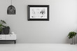 © Photographee.eu - Black lamp above white cabinet with plant in empty grey flat interior with poster. Real photo. Place for your sofa