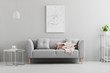 © Photographee.eu - Poster above grey sofa with pink blanket in living room interior with white lamp and plant. Real photo