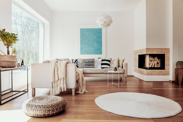 Beige and white textiles and a modern spherical pendant light in a sunny, tranquil living room interior with natural decor.