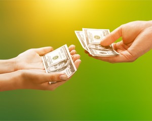 Giving hands with dollars on blurred background