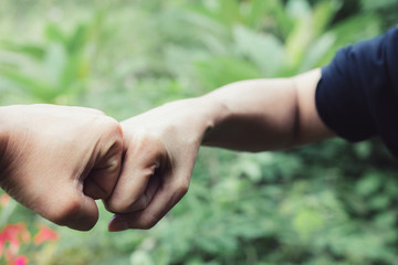 closeup hand of person team work fist bump in nature background.