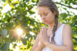 © PhotoGranary - Christian worship and praise. A young woman is praying in the early morning with sun in the background.