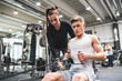 © Halfpoint - Young man in gym with his personal trainer working out on cable weight machine.
