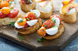 Crostini or bruschetta board with caprese made with roasted tomatoes