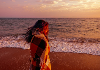 Wall Mural - Woman walking on coast at sunset.