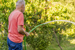 © Mihail - senior old man pouring harvest with water in summer garden outdoor