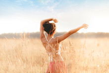 Young attractive girl dancing in field at sunset