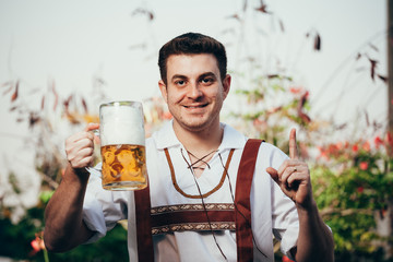 Man in traditional bavarian clothes holding mug of beer