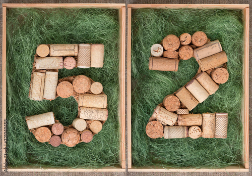 Fotografia Number 52 fifty two made of wine corks on green background in wooden box