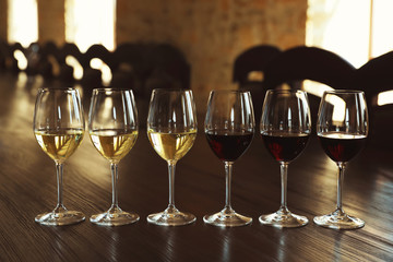 Canvas Print - Glasses of white and red wines on wooden table