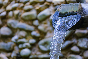 water flows from a wooden pipe or water gushing out of the pipe close up