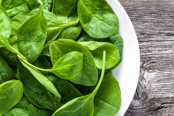 Wall Mural - Fresh organic spinach on plate, leafy green vegetables, healthy food concept