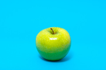 Single green fresh apple on blue background